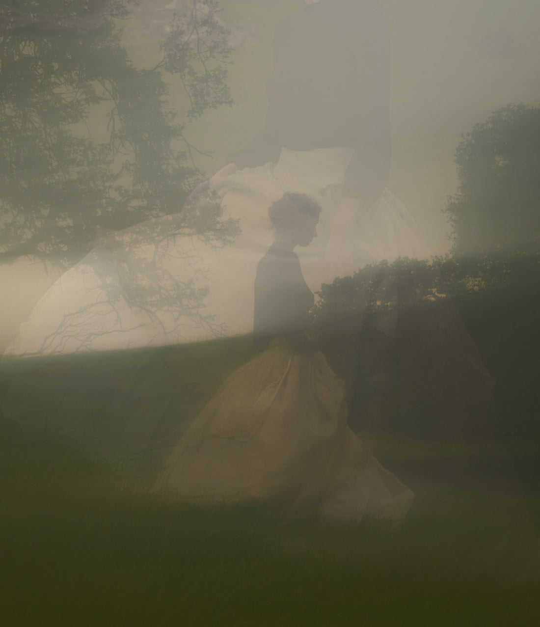 Person walking on a path with tents in the background, surrounded by trees and fog.