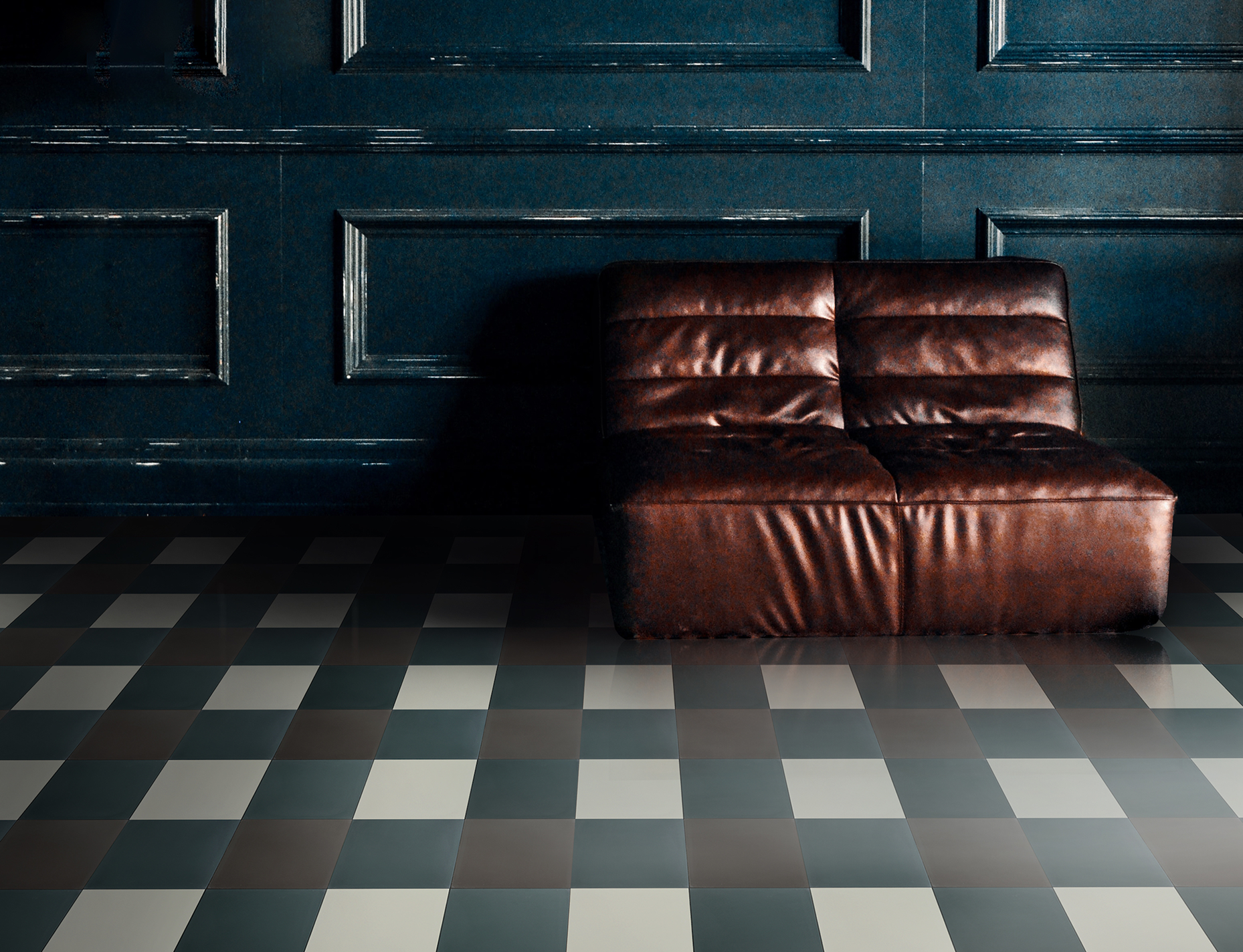 A leather sofa on a green and white checkered cement floor