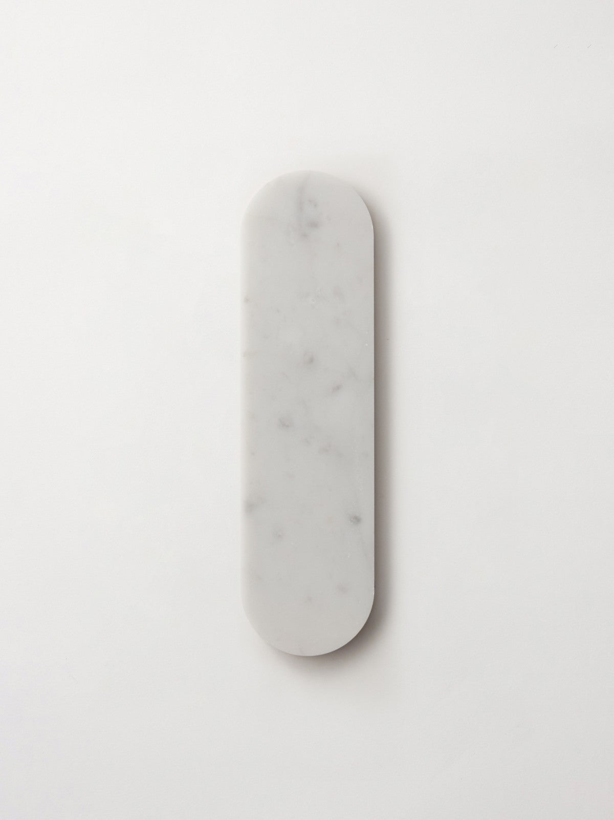 an oval white marble tile on a white surface.