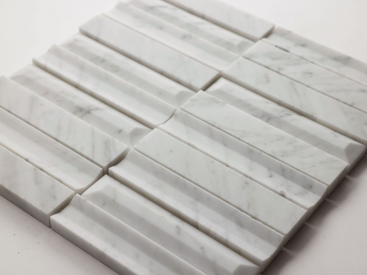 Rectangular white marble tiles with subtle gray veining are arranged in a grid pattern, with each tile featuring a raised, textured surface.