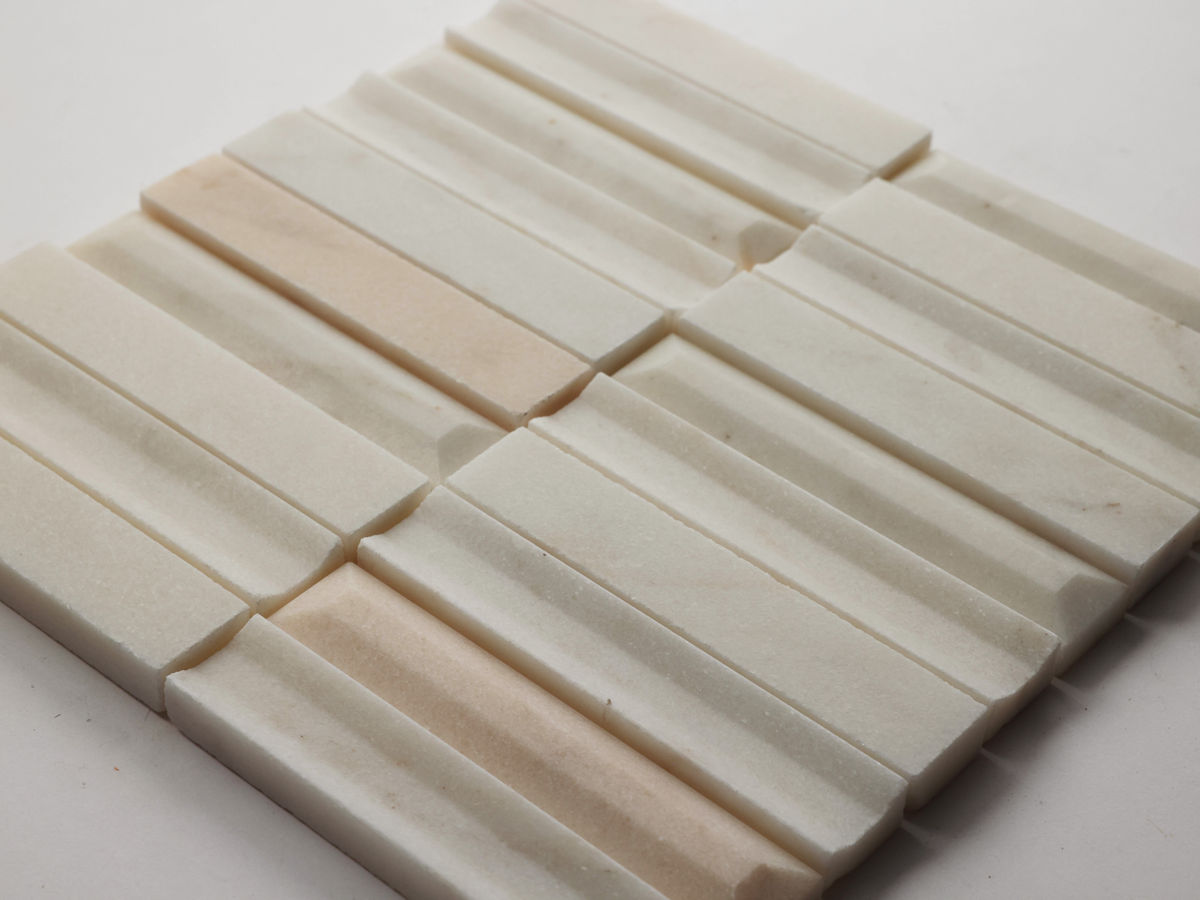 A close-up of a square tile panel composed of rectangular, cream-colored, ridged stone pieces with slight variations in shade.