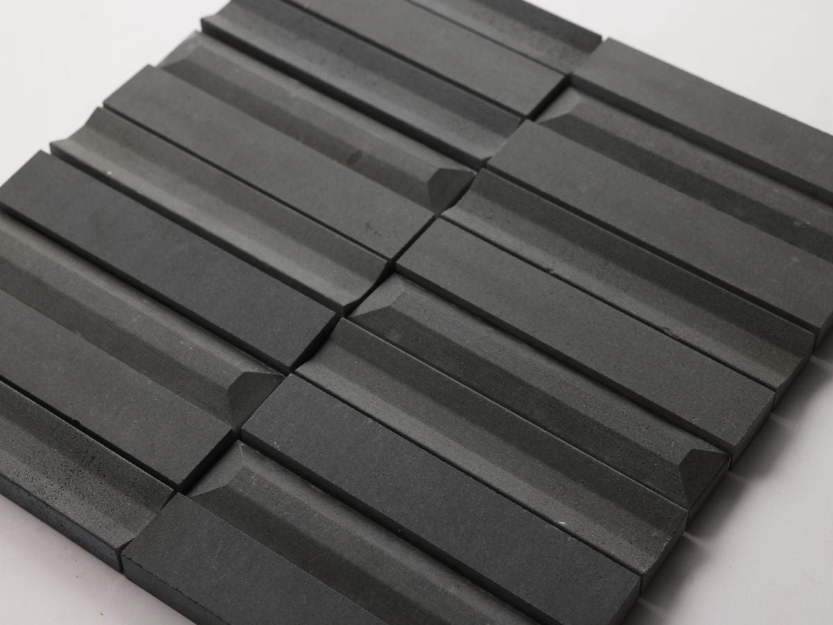 Rectangular black tiles with grooved and beveled surfaces are arranged in a grid pattern on a white background.