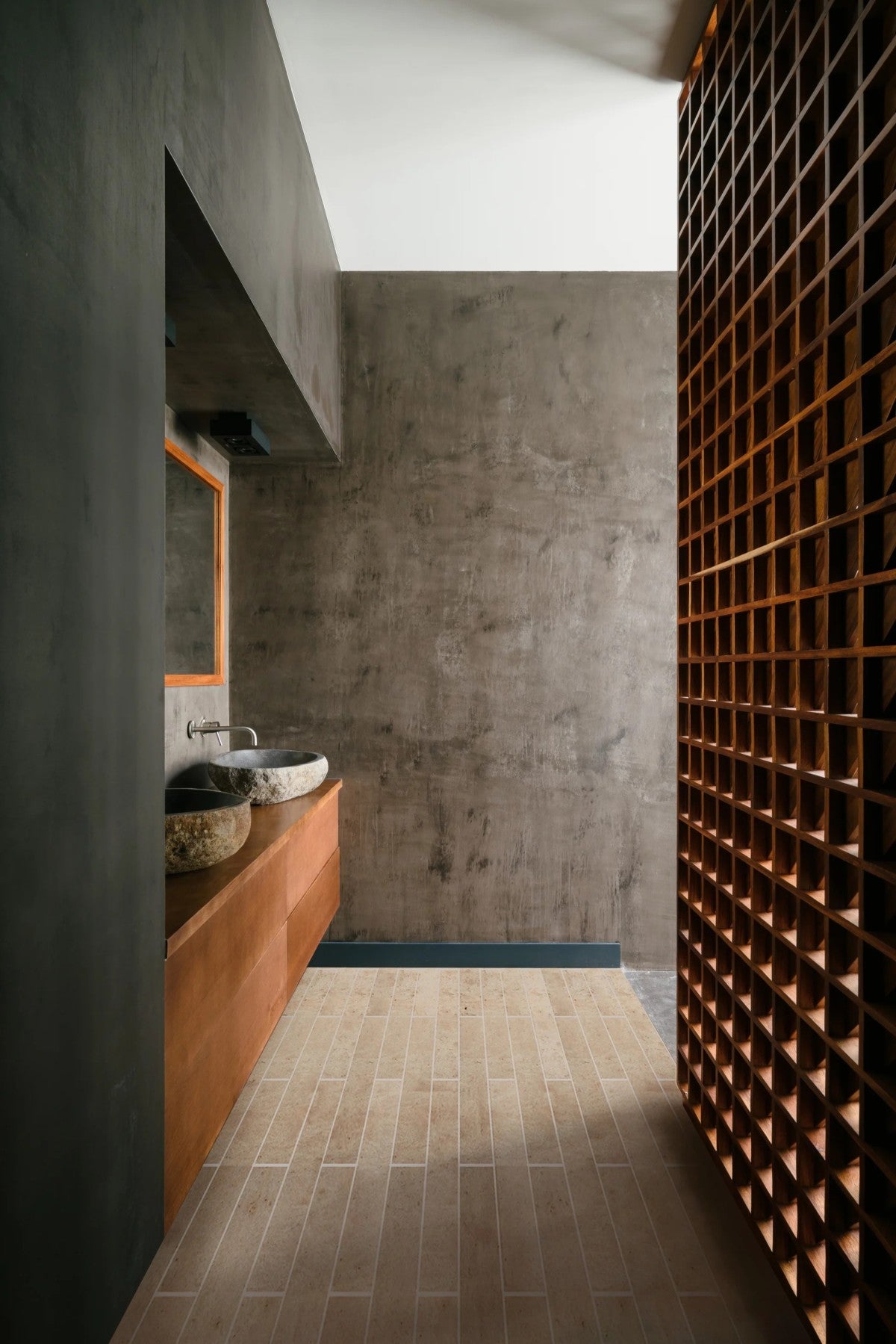 Modern bathroom with a stone sink, wooden vanity, textured gray walls, beige tile floor, and a slatted wooden partition on the right.