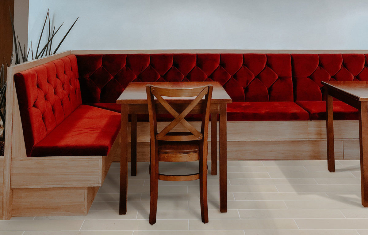 a wooden table with a chair and a red upholstered bench.
