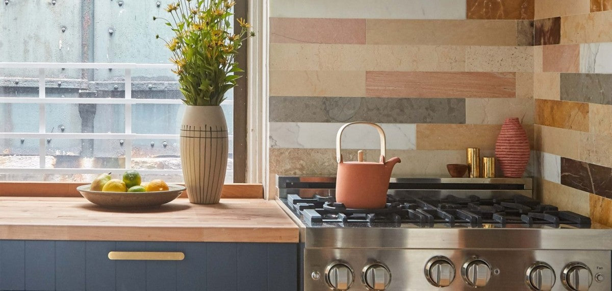 a kitchen with a stove, a window and a tile backsplash.