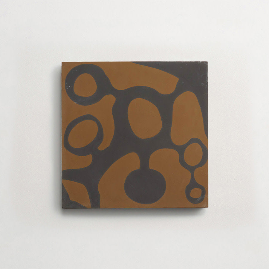 A square canvas with abstract organic shapes in brown and dark gray on a plain white wall.