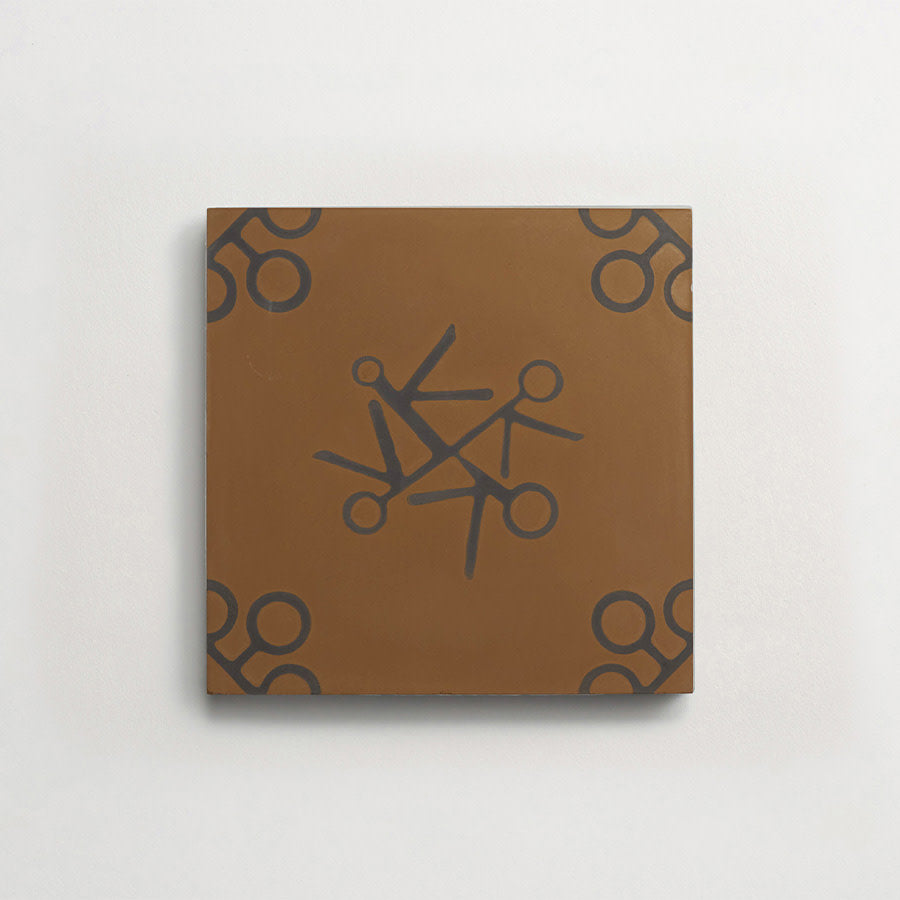 A brown square tile with black scissor illustrations arranged in a circular pattern at the center and in each corner, mounted on a plain white wall.