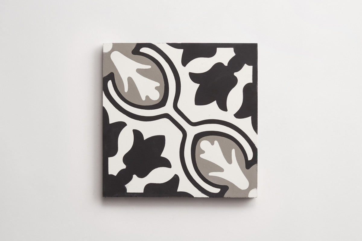 A square ceramic tile with a black, white, and gray abstract leaf pattern on a white background.
