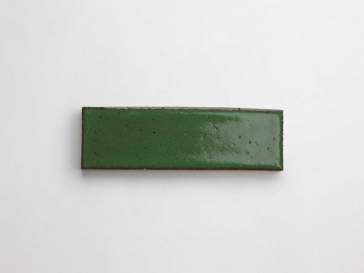 A rectangular green ceramic tile with a glossy finish on a plain white background.