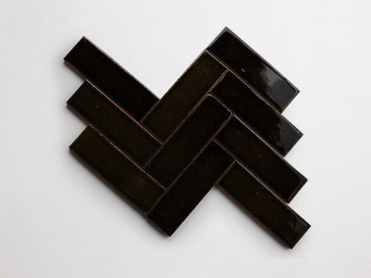 Five glossy black rectangular tiles are arranged on a white background in a herringbone pattern.