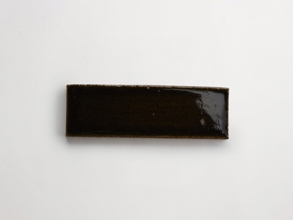 A rectangular slab coated with a glossy, dark brown surface rests on a plain white background.