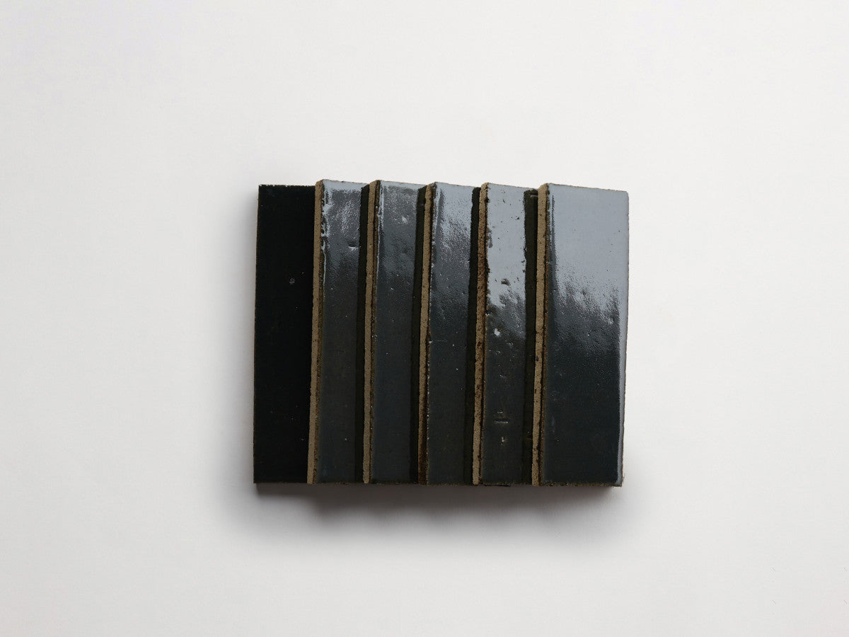Six rectangular, glossy black tiles are arranged vertically in a row on a plain white background.