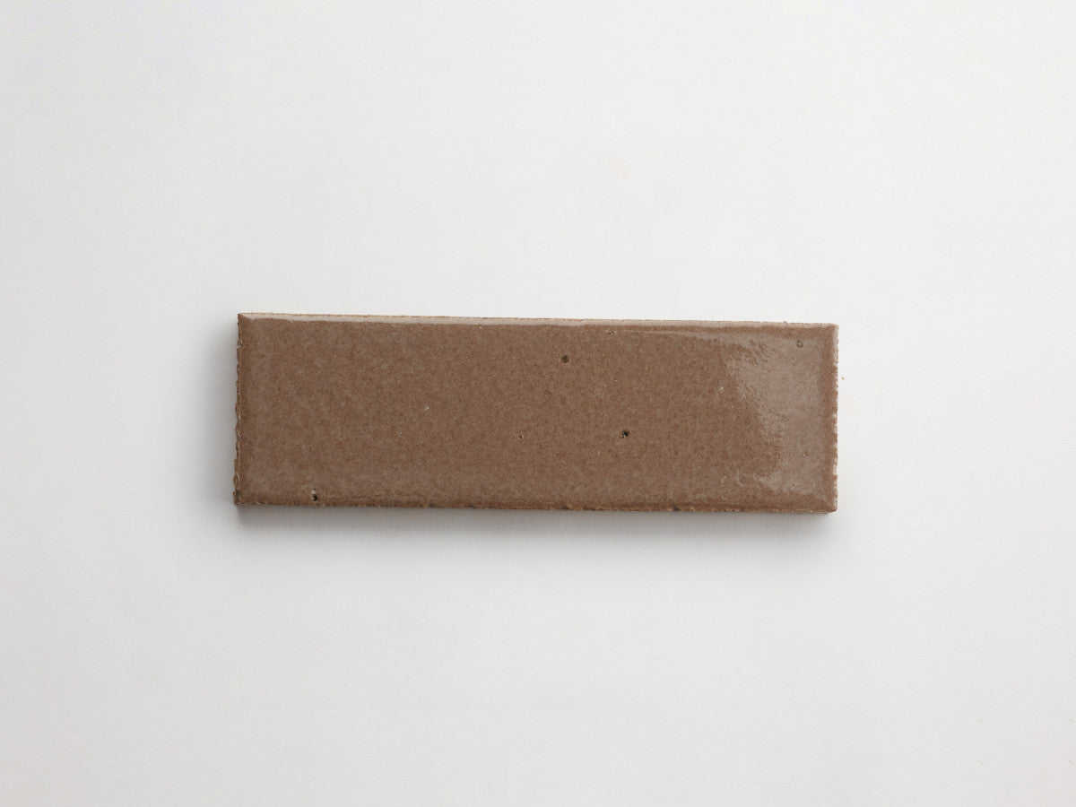A single rectangular brown ceramic tile with a glossy finish on a plain white background.
