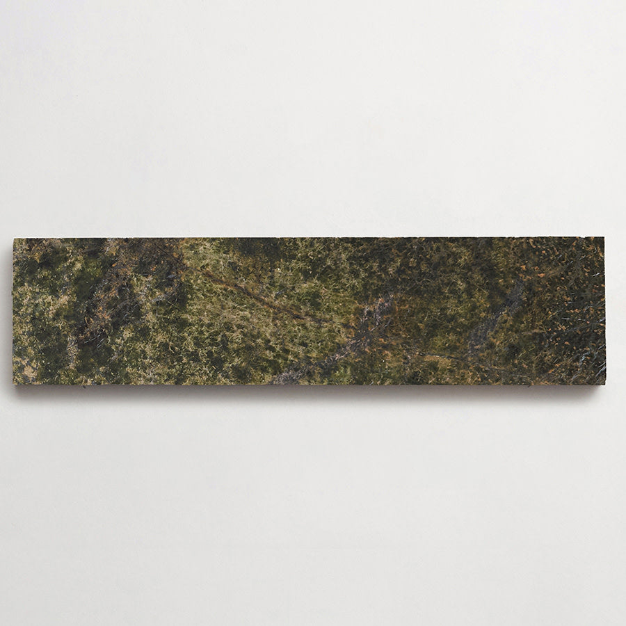 A rectangular, narrow artwork with a textured, earth-toned surface resembling a landscape, mounted on a plain white wall.