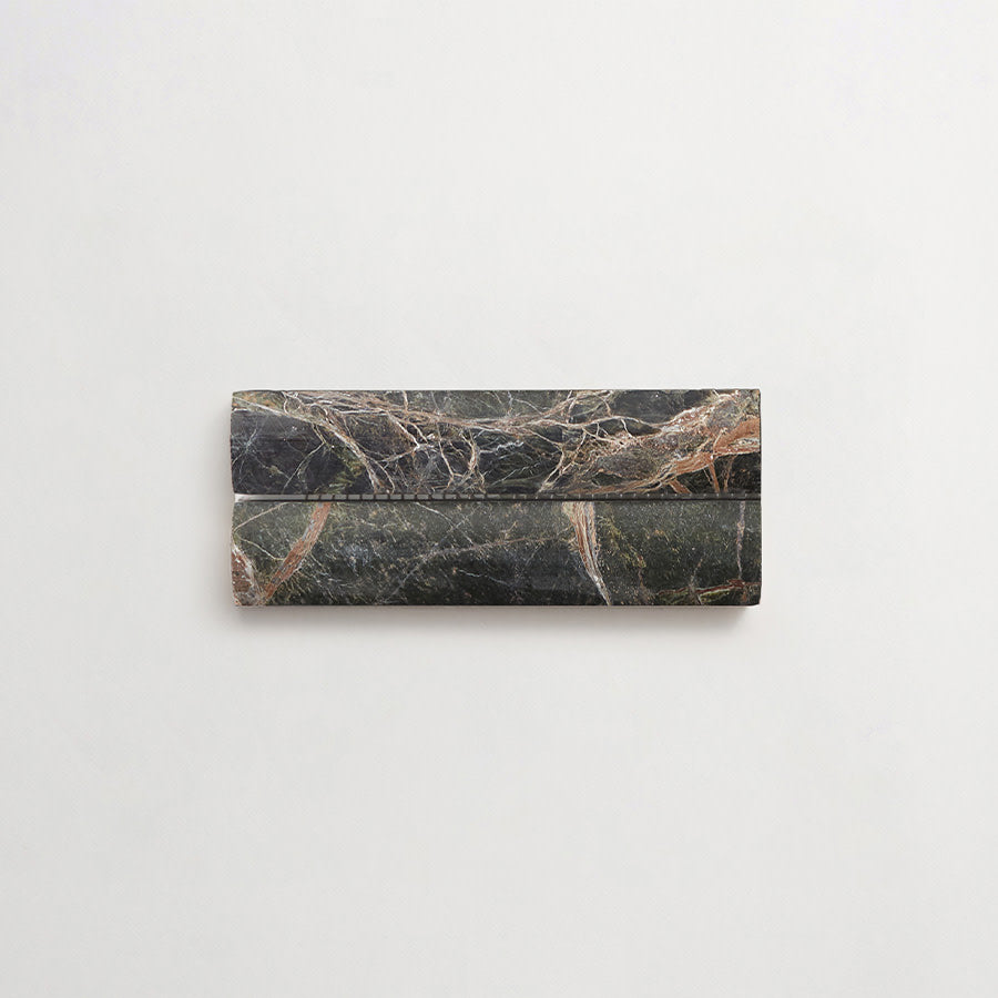 A rectangular, dark marble object with natural veins and lines lies against a plain, light background.