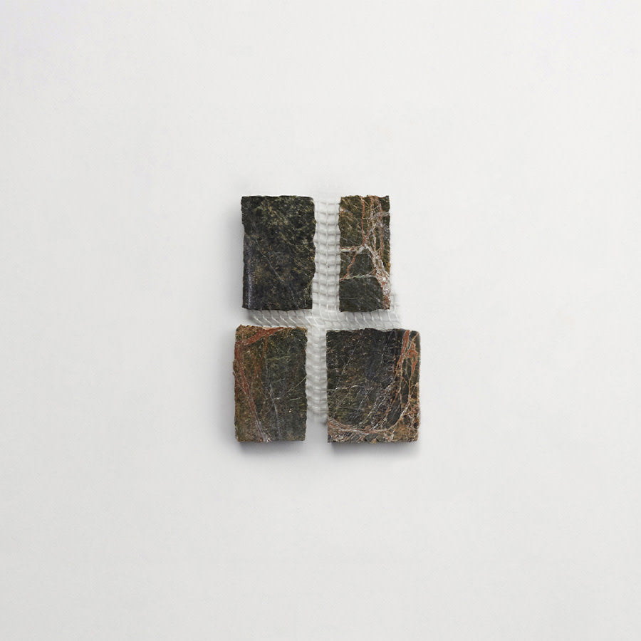 Four rectangular pieces of dark, veined stone are arranged in a grid with a vertical line of bubble wrap separating the two columns, all set against a plain white background.