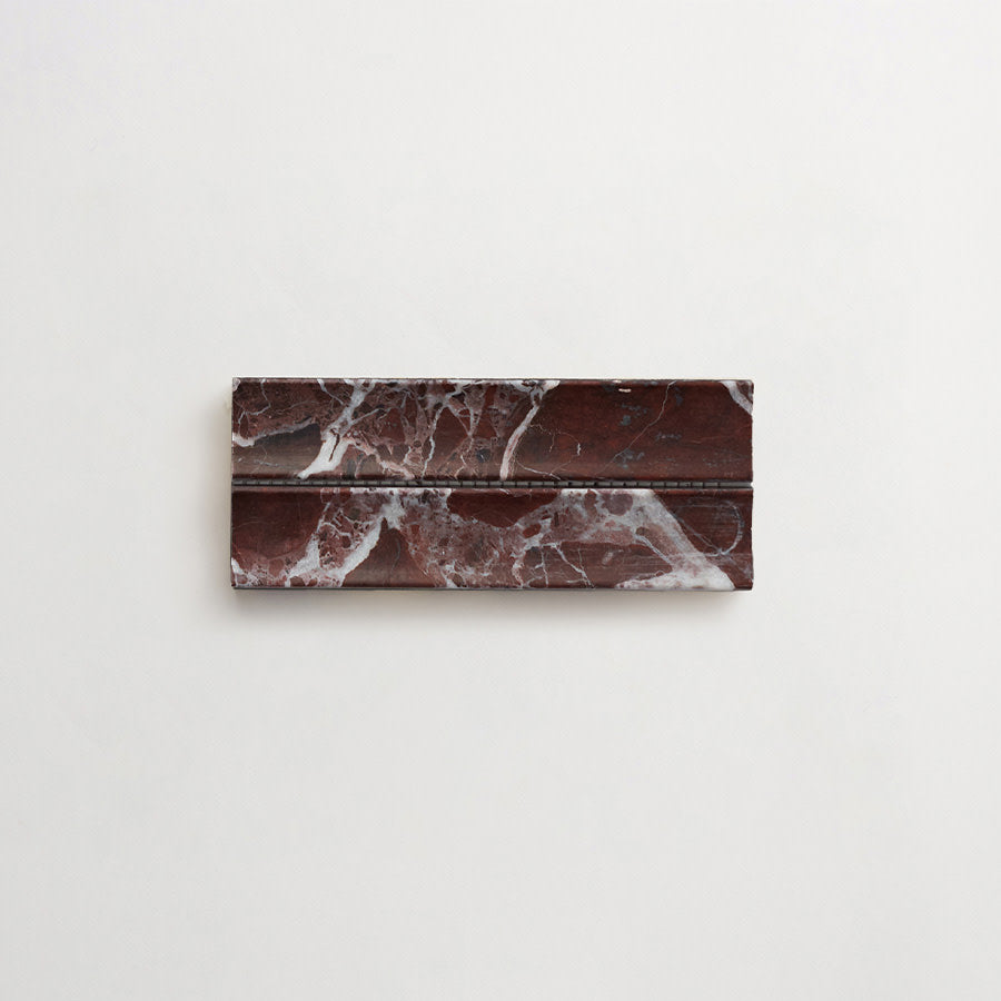 Rectangular piece of dark red marble with white veining, featuring a groove across its surface, placed on a plain light background.