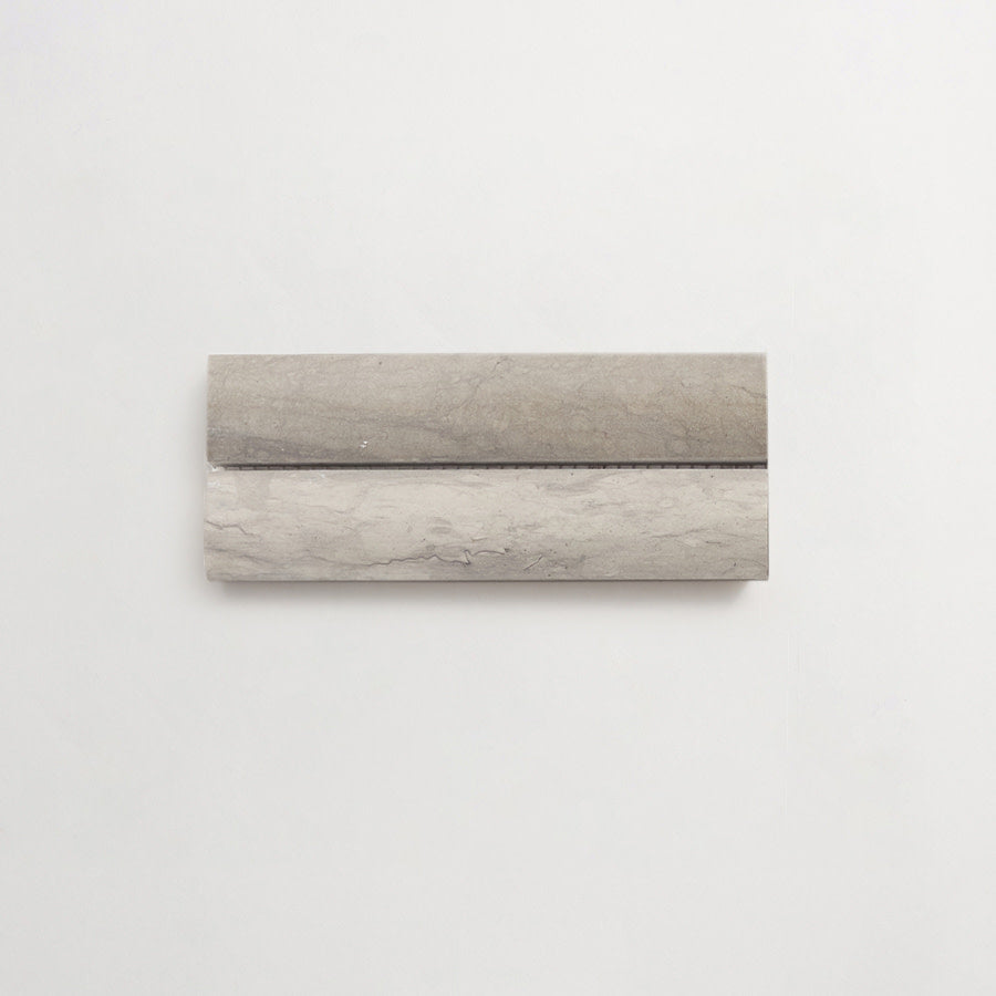 A rectangular, gray marble slab with a horizontal groove is mounted on a plain white wall.