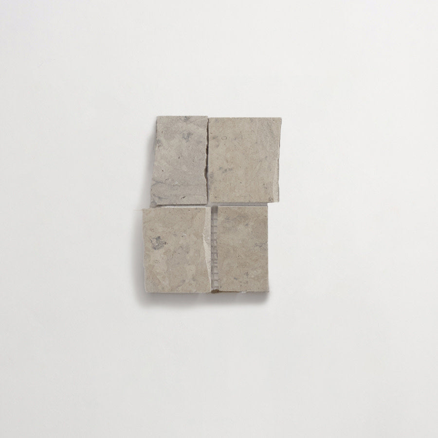 Four uneven, square stone tiles are arranged in a grid pattern on a plain white background, with visible gaps between each tile.