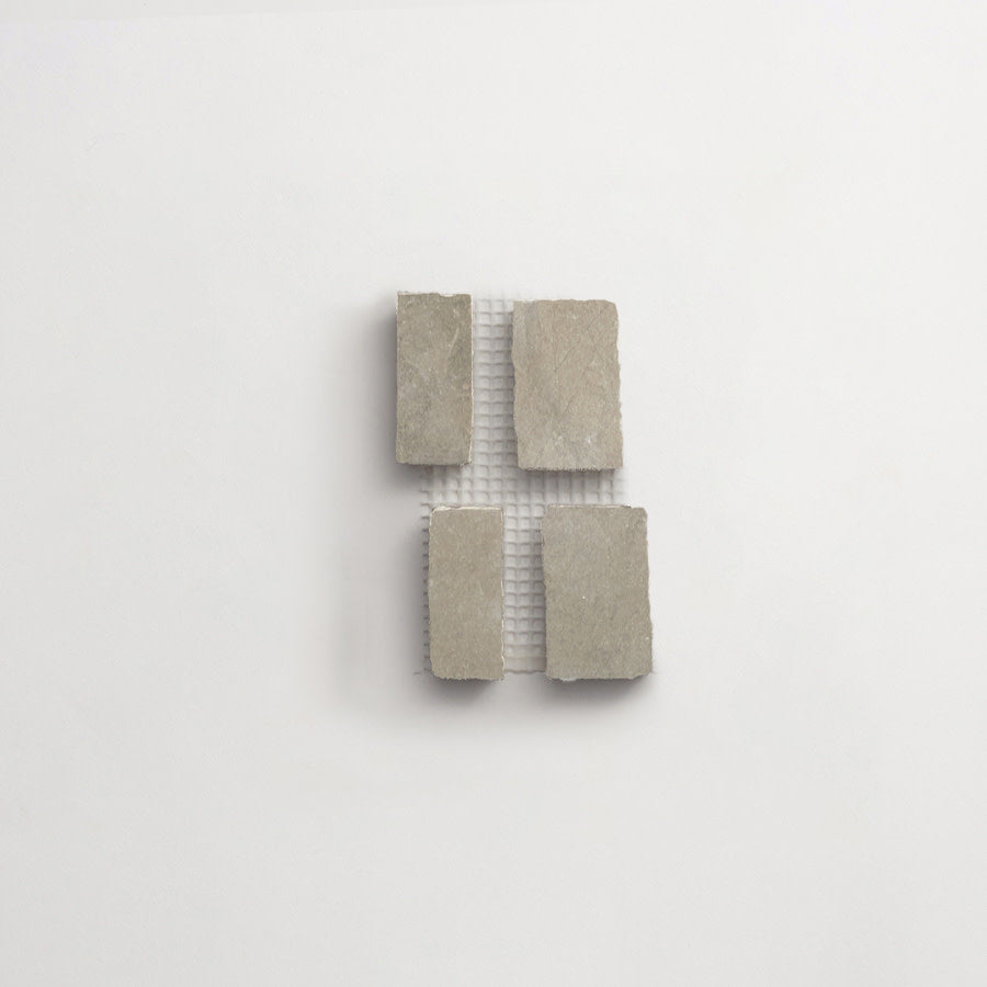 Four rectangular stone tiles are arranged in a grid pattern on a white mesh backing against a plain white background.