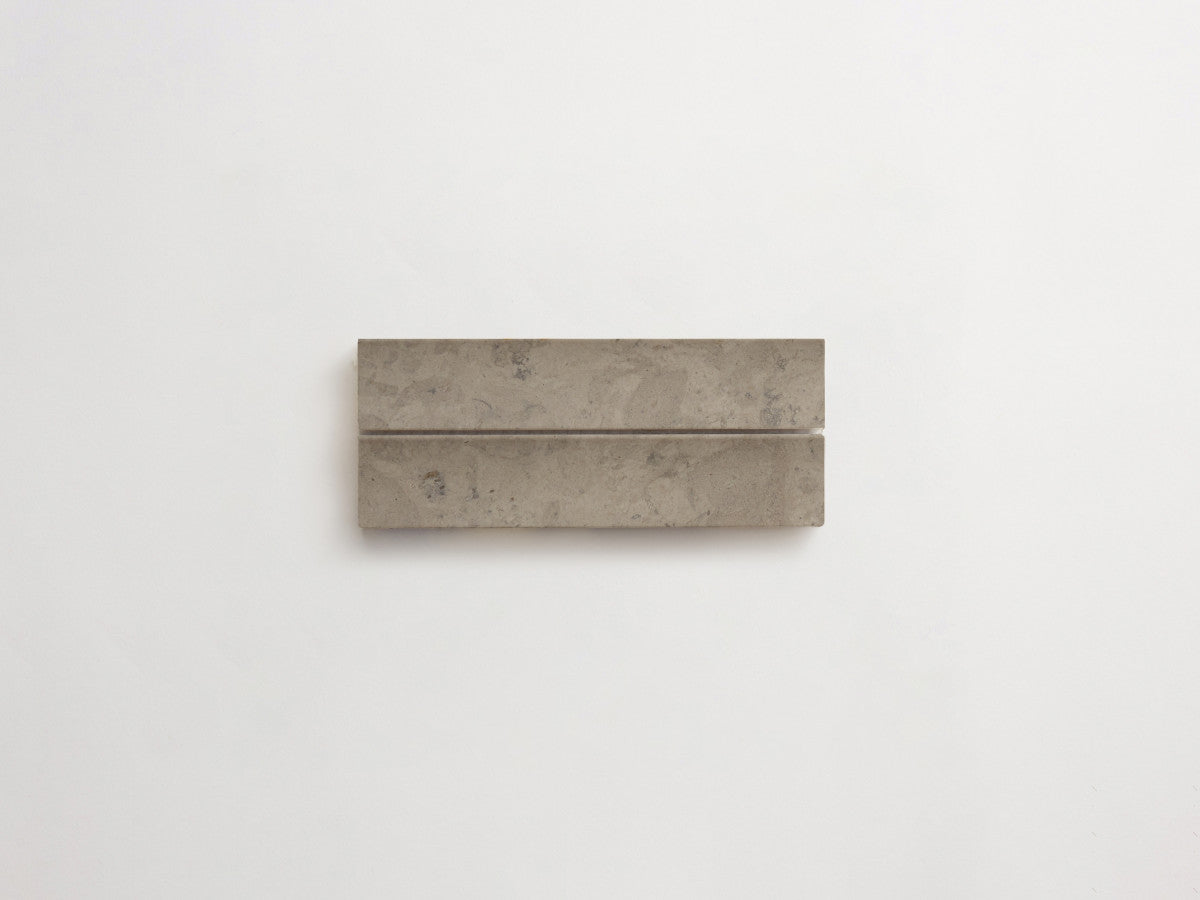 A rectangular gray concrete block with a narrow groove running horizontally near the top, placed on a plain white background.