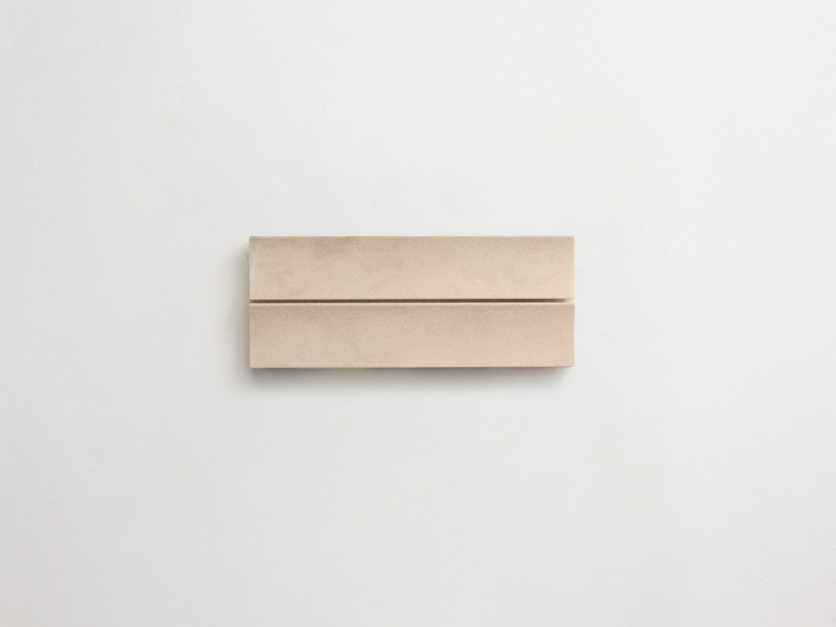 A rectangular beige object with a thin horizontal groove across the middle, placed on a plain white background.