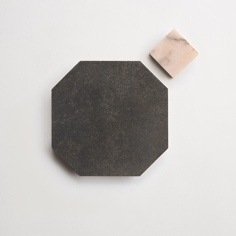 A large, black octagonal tile sits next to a smaller, square, light pink marble tile on a plain white background.