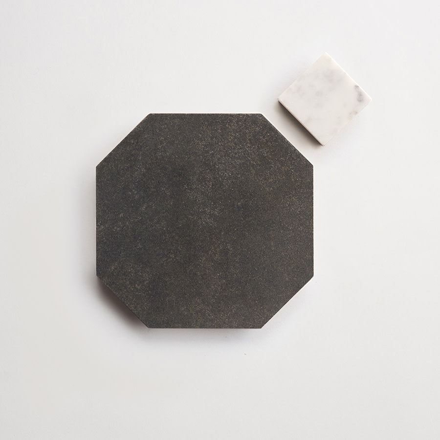 A large, dark octagonal tile sits next to a small, white square tile on a light background.