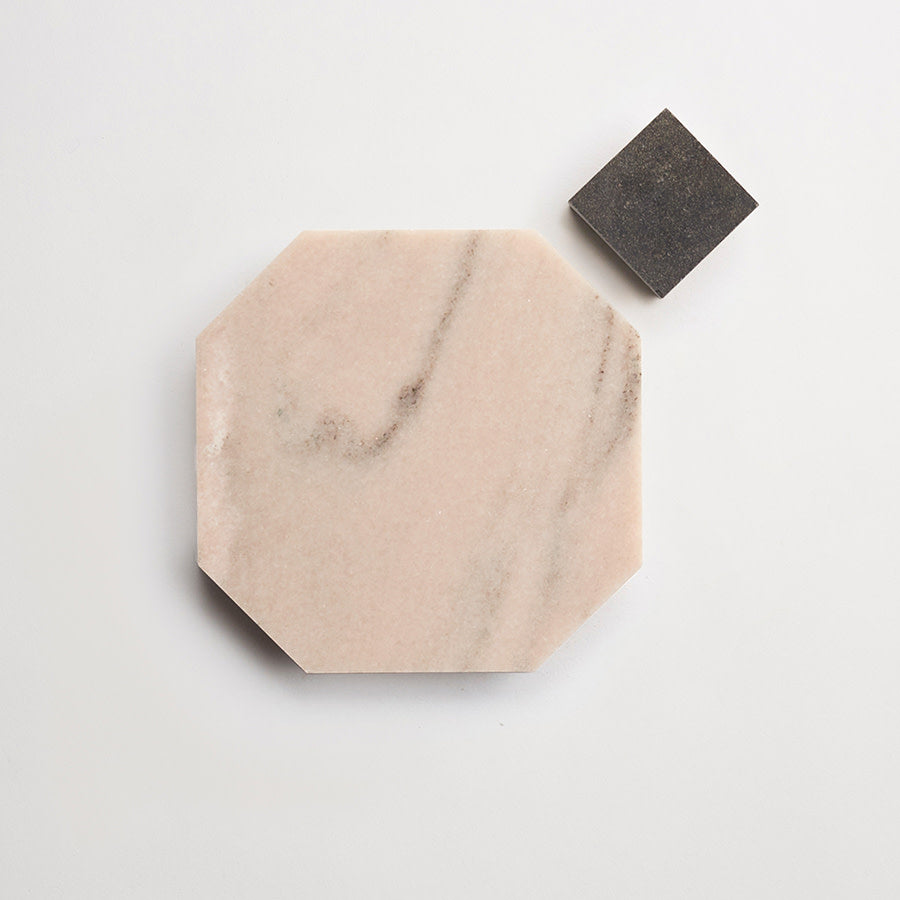 A pink octagonal marble tile and a small dark square tile are placed on a white background.