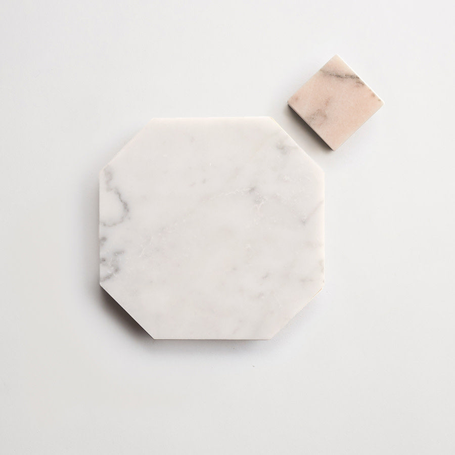 An octagonal white marble tile and a smaller square beige tile are placed on a plain white background.