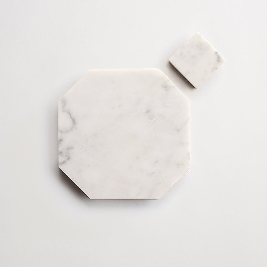 Two white marble slabs on a white surface: one is a large octagon, and the other is a small square placed near the top right corner of the octagon.