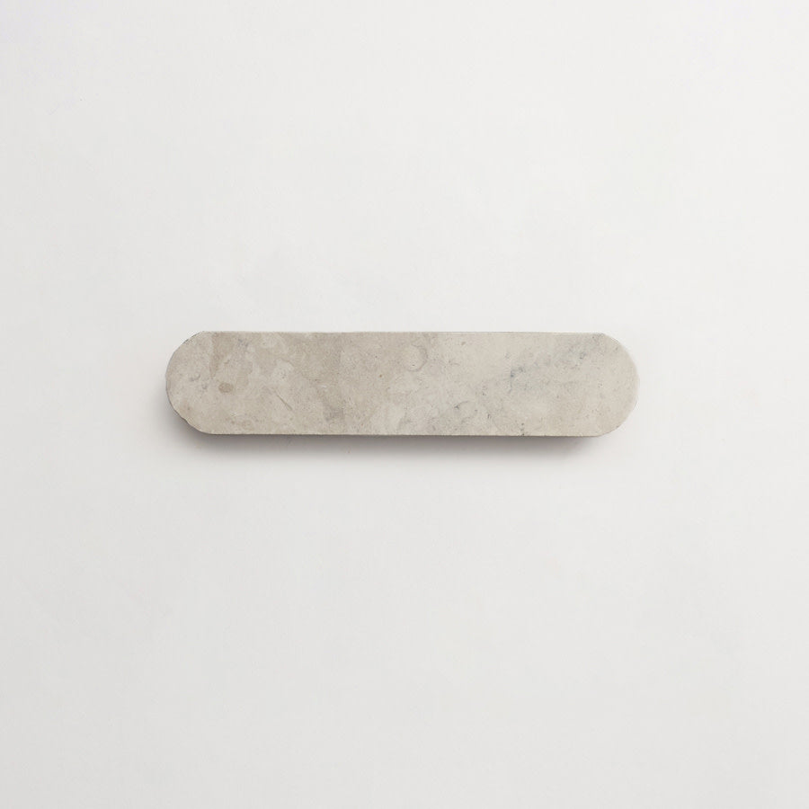 A flat, elongated oval-shaped stone slab with rounded ends placed on a plain white background.