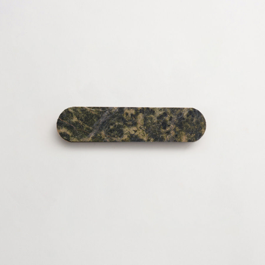A dark green and brown rectangular object with rounded ends is centered on a plain white background.