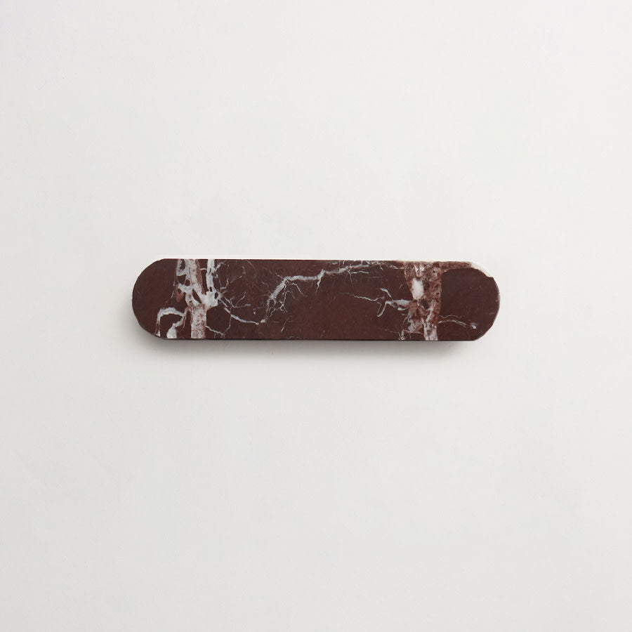 A rectangular, dark brown marble object with rounded ends and white veining, placed on a plain white background.
