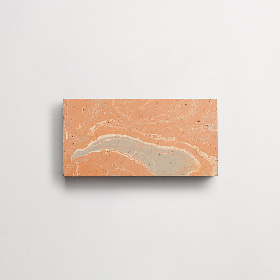 A rectangular tile with a marbled pattern in shades of orange, beige, and light gray, set against a plain white background.