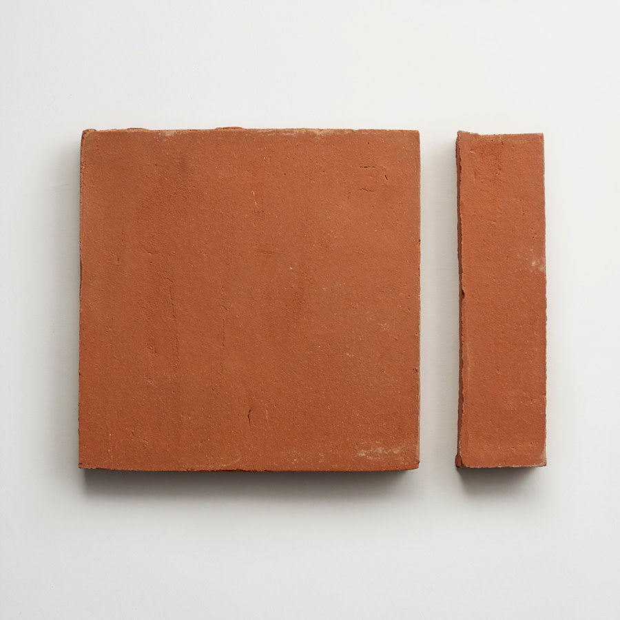 Two red clay bricks on a white background; one is a large square, and the other is a narrower rectangular piece placed vertically beside it.