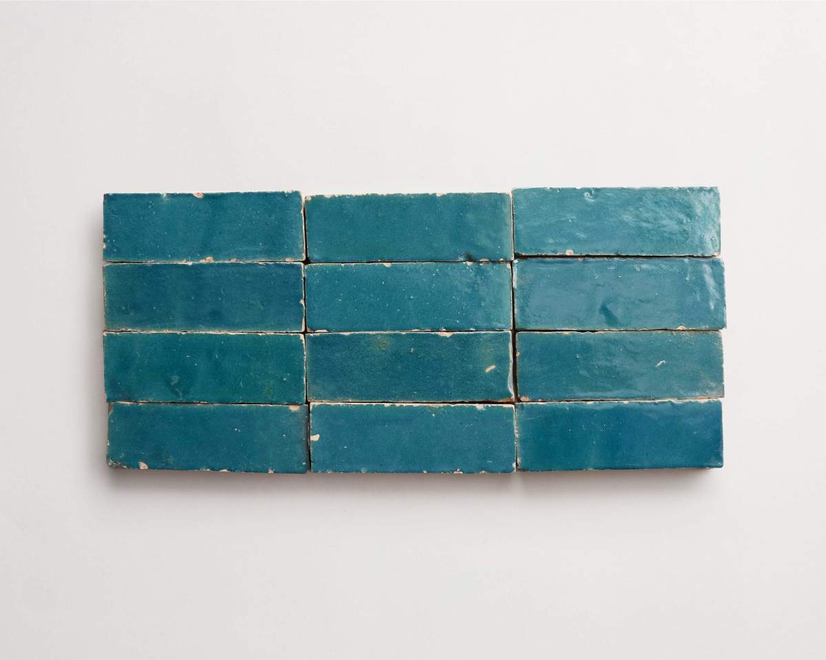 Twelve rectangular blue ceramic tiles are arranged in three rows of four on a plain white background.