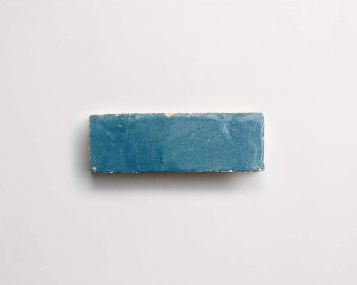 A rectangular blue tile with slightly rough edges is placed on a plain white background.
