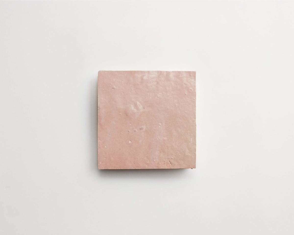 A single square, light pink tile with a slightly uneven surface, centered on a plain white background.