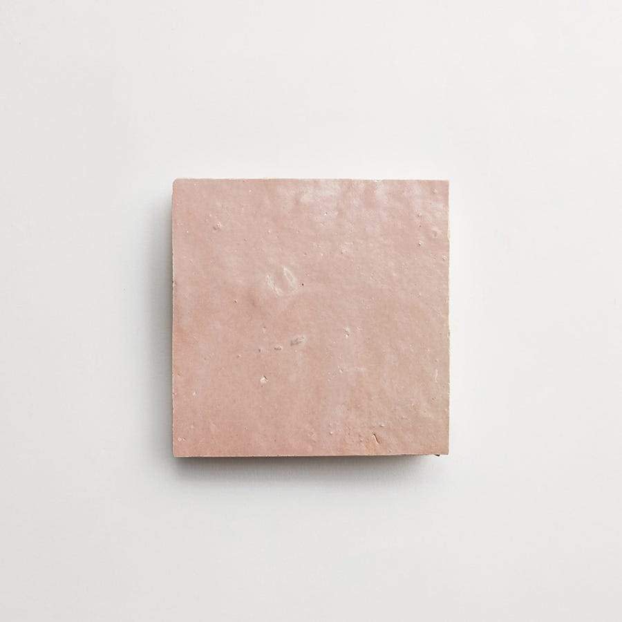 A single square pink ceramic tile is centered on a plain white background.