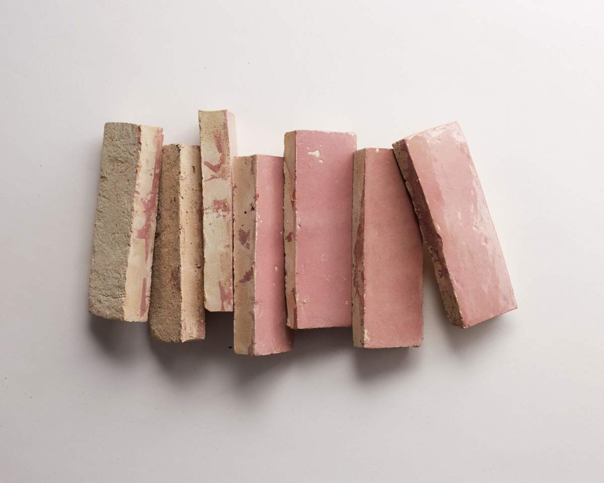 Seven rectangular pink and beige bricks are arranged vertically side by side on a white background.