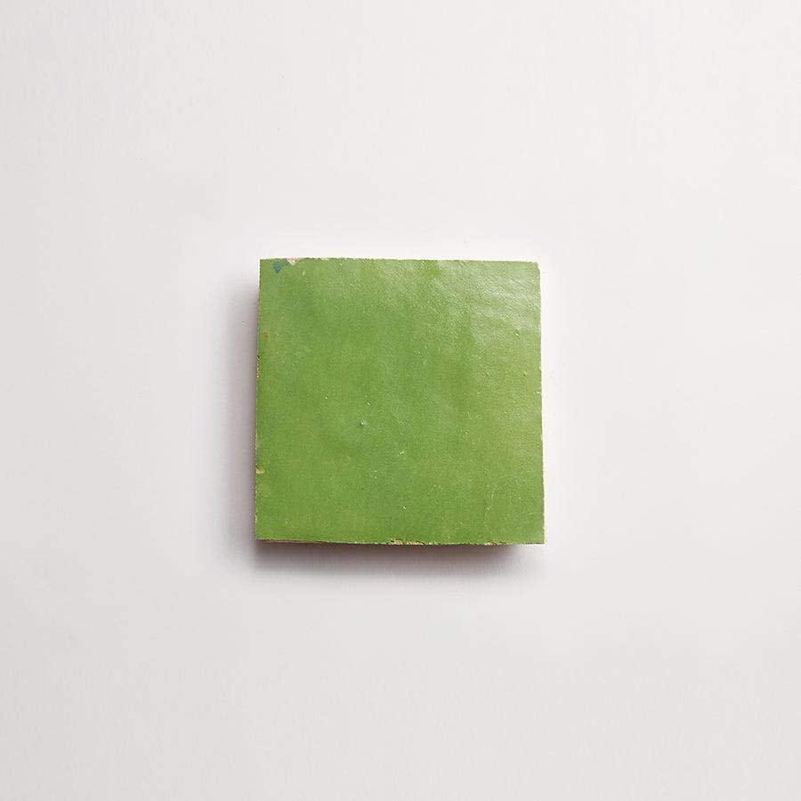 A single green square tile on a plain white background.