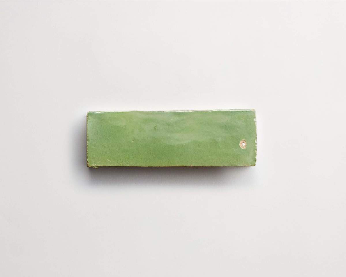 A rectangular green ceramic tile is centered on a plain white background.