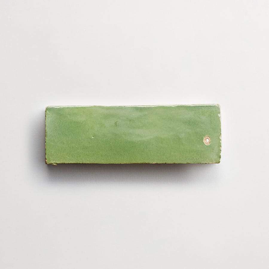 A rectangular, green ceramic tile with a glossy finish is pictured against a plain light background.
