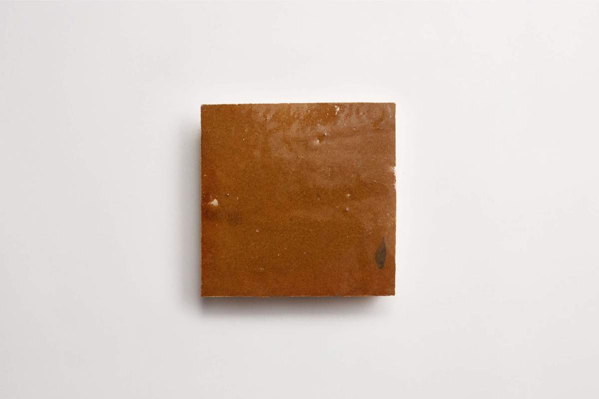 A square piece of brown material, possibly soap or clay, is placed on a plain white background.