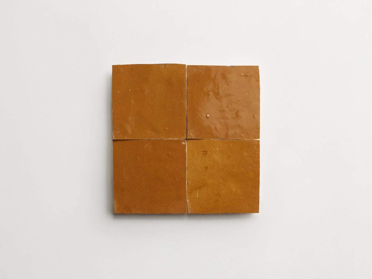 Four square, brown ceramic tiles arranged in a 2x2 grid on a plain white background.