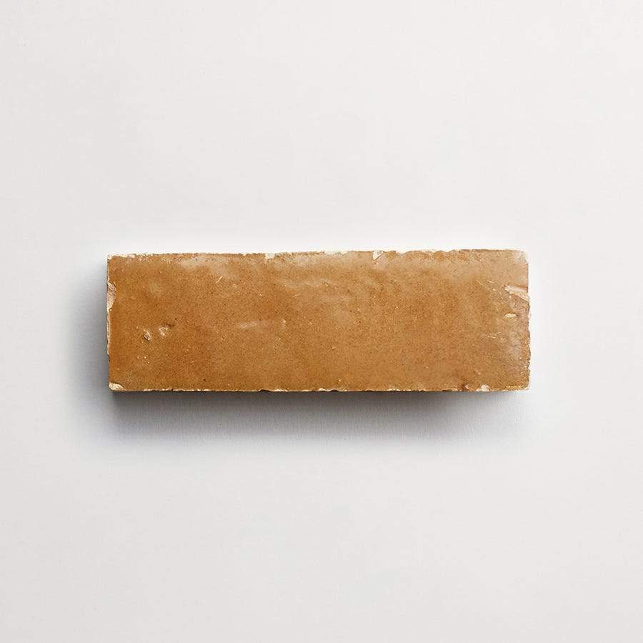 A single rectangular brown brick is placed on a plain white surface.