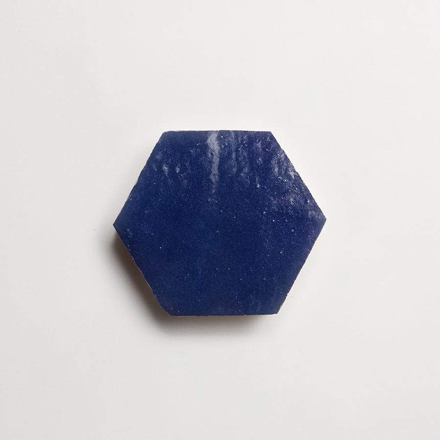 A blue hexagonal object with a slightly rough texture is centered on a plain white background.