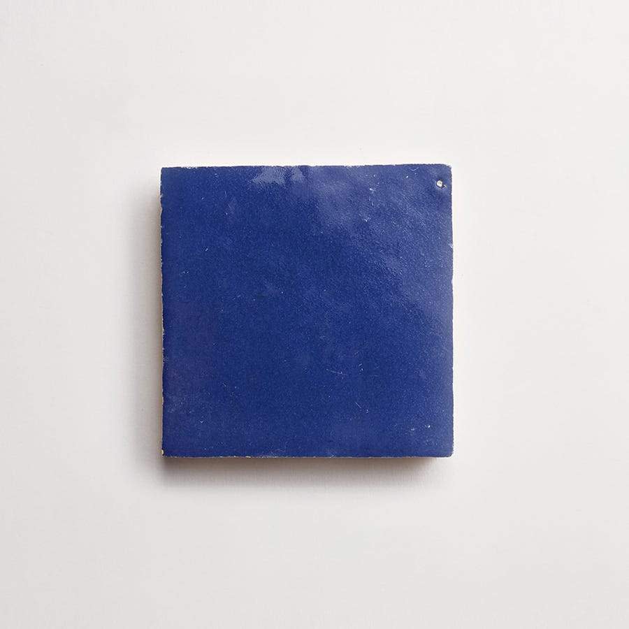 A single square blue ceramic tile displayed on a plain white background.