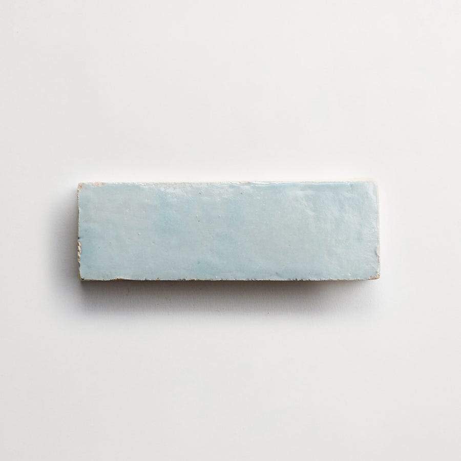 A rectangular, light blue ceramic tile with a glossy finish is centered on a plain white background.